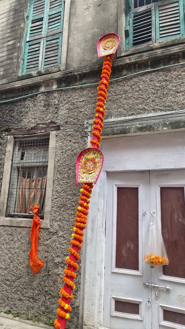 The khuti, garlanded with marigolds, against an old house of the para